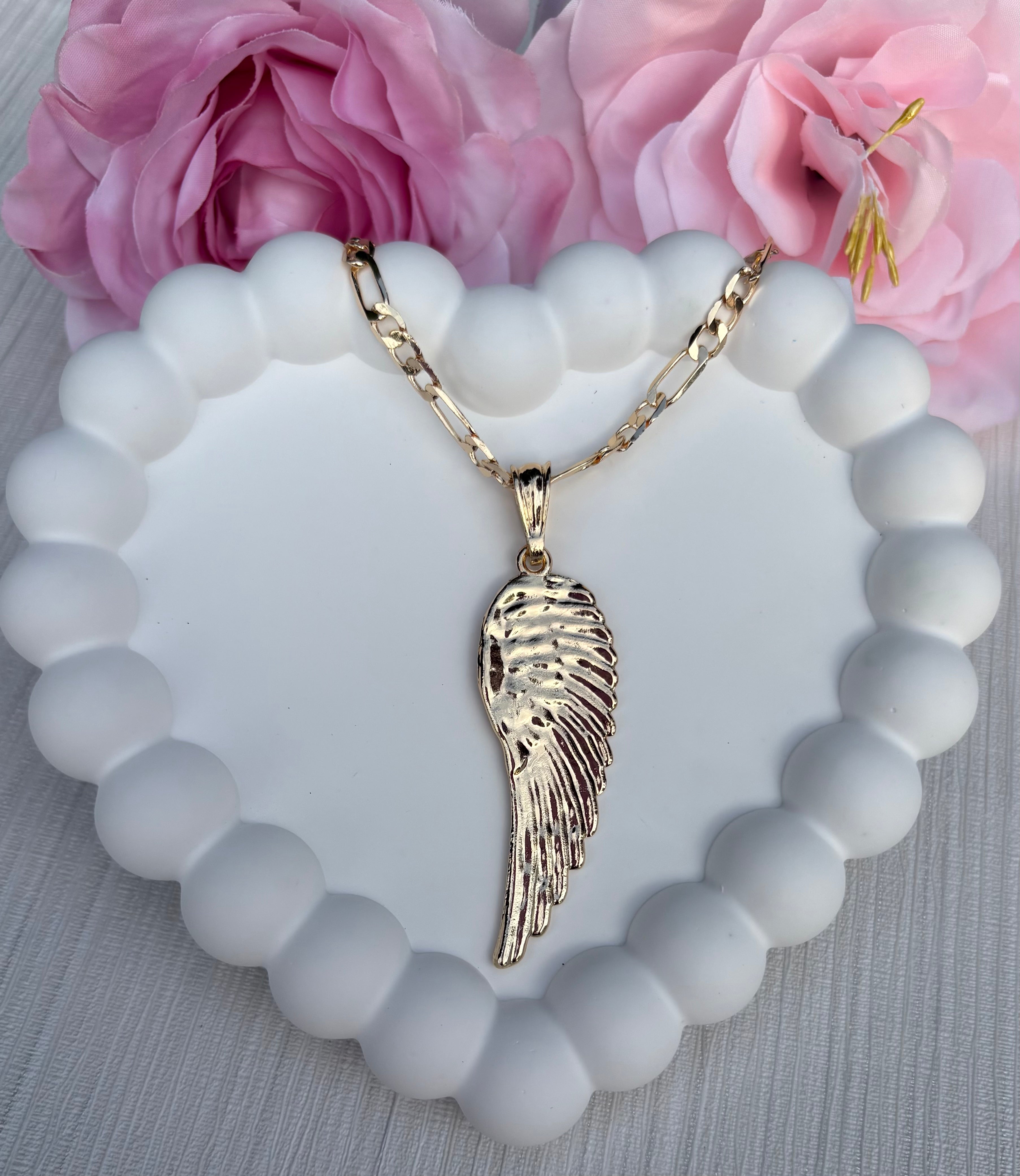 Gold angel wing necklace displayed on white background, featuring delicate chain and shiny wing pendant.