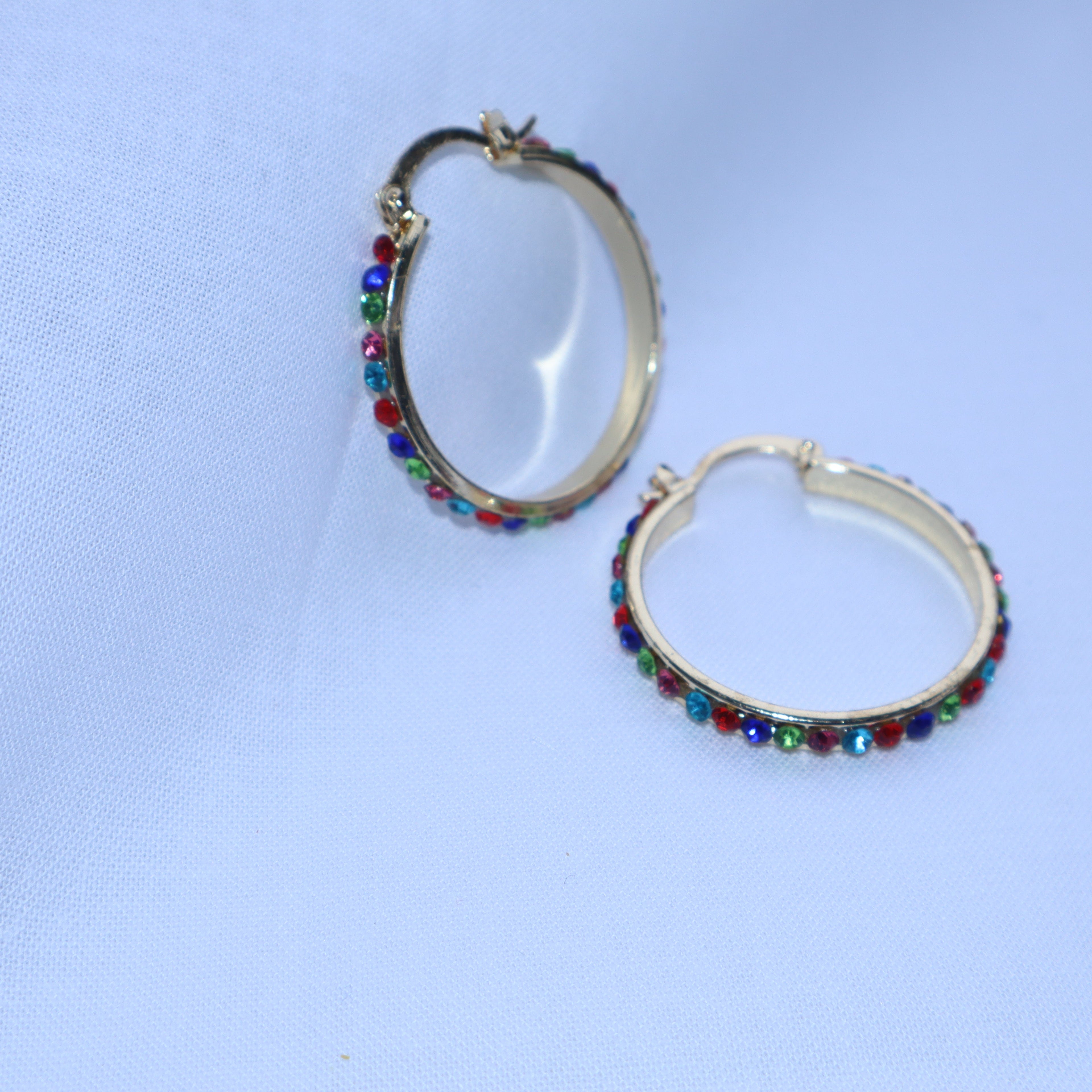 Pair of hoop earrings with colorful beads on a light blue background