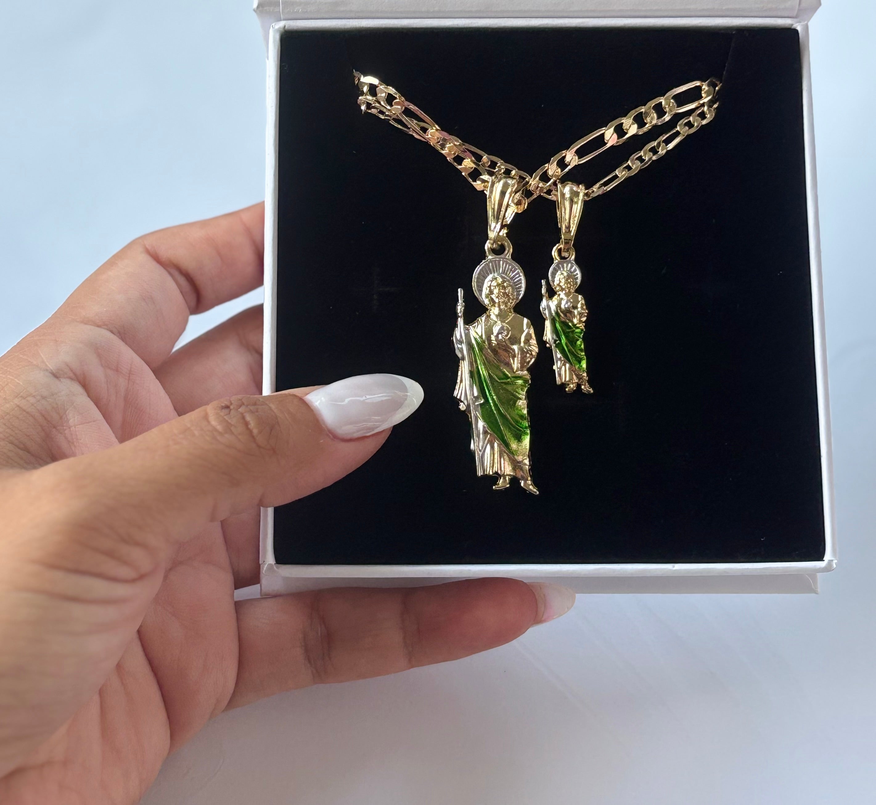 San Judas Tadeo Figaro Necklace set with two pendant sizes, shown inside a black jewelry box with hand holding it.