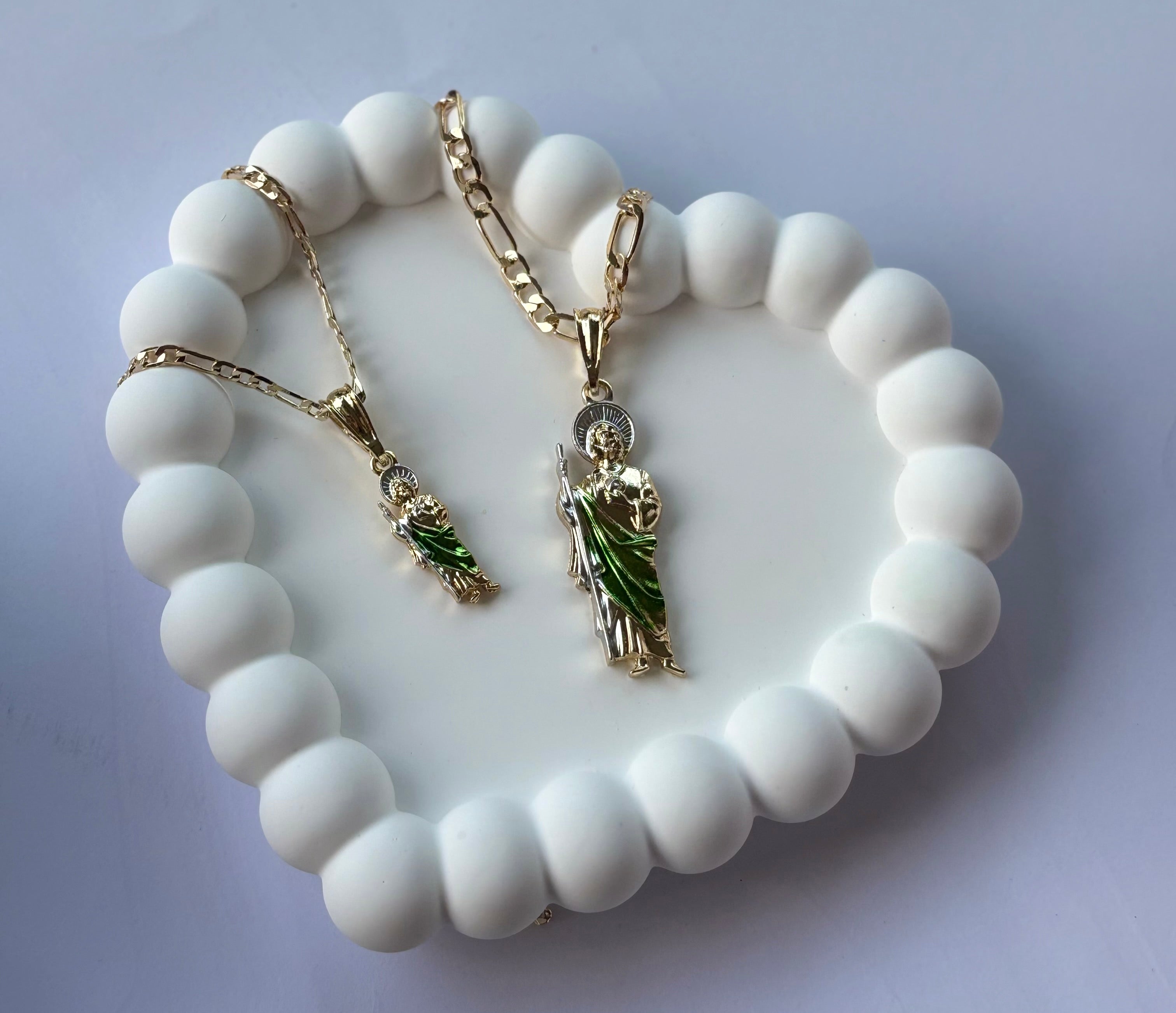 San Judas Tadeo Figaro Necklace with small and large pendants, displayed on a white beaded heart tray.
