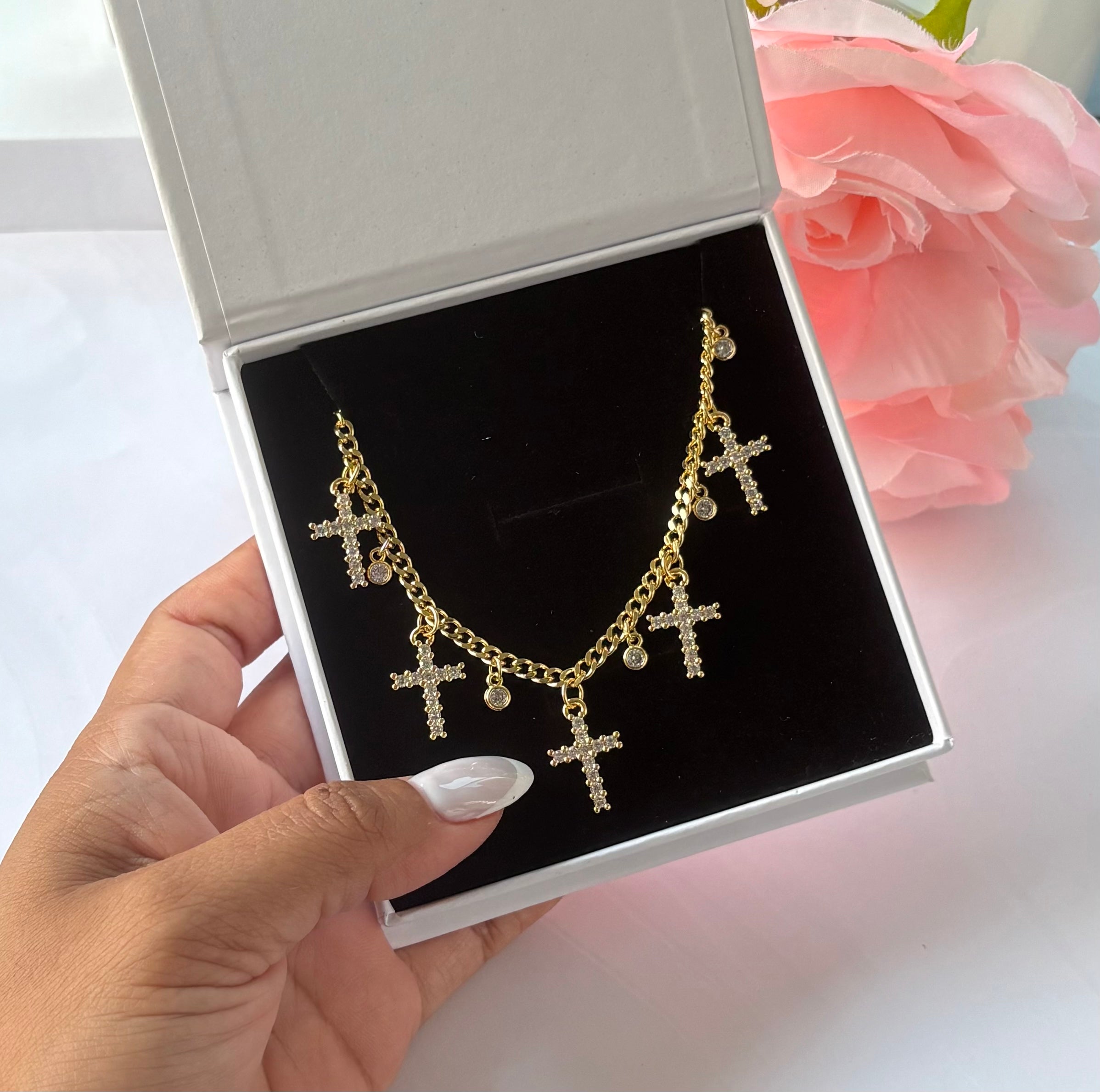 Gold-plated necklace with multiple crystal cross charms and round crystal drops, displayed in white gift box.